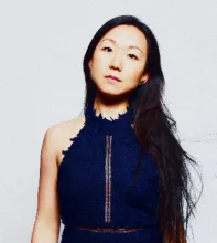 Linda May Han Oh poses confidently in a navy blue halter dress.