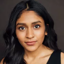 Michelle Mohammed with long dark hair and expressive eyes, smiling softly against a neutral background.