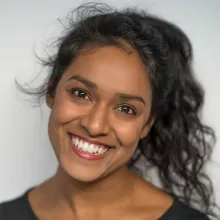 Miriam Fernandes with curly dark hair, wearing a black top, against a soft, light background.