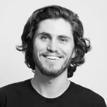 Sturla Alvsvåg with curly hair and a beard, wearing a black shirt against a light background.
