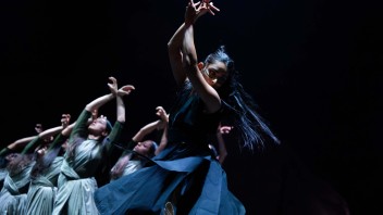 Group of stage dancers reaching upward in dramatic low-light photograph