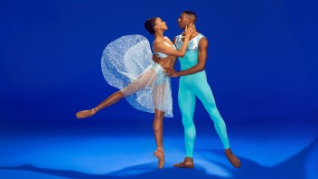 Ballet dancers on vivid blue background; ballerina in white tutu with leg up while her partner in turquoise supports her