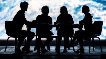 Silhouettes of four people seated at a table, backdrop featuring a blurred cosmic scene.