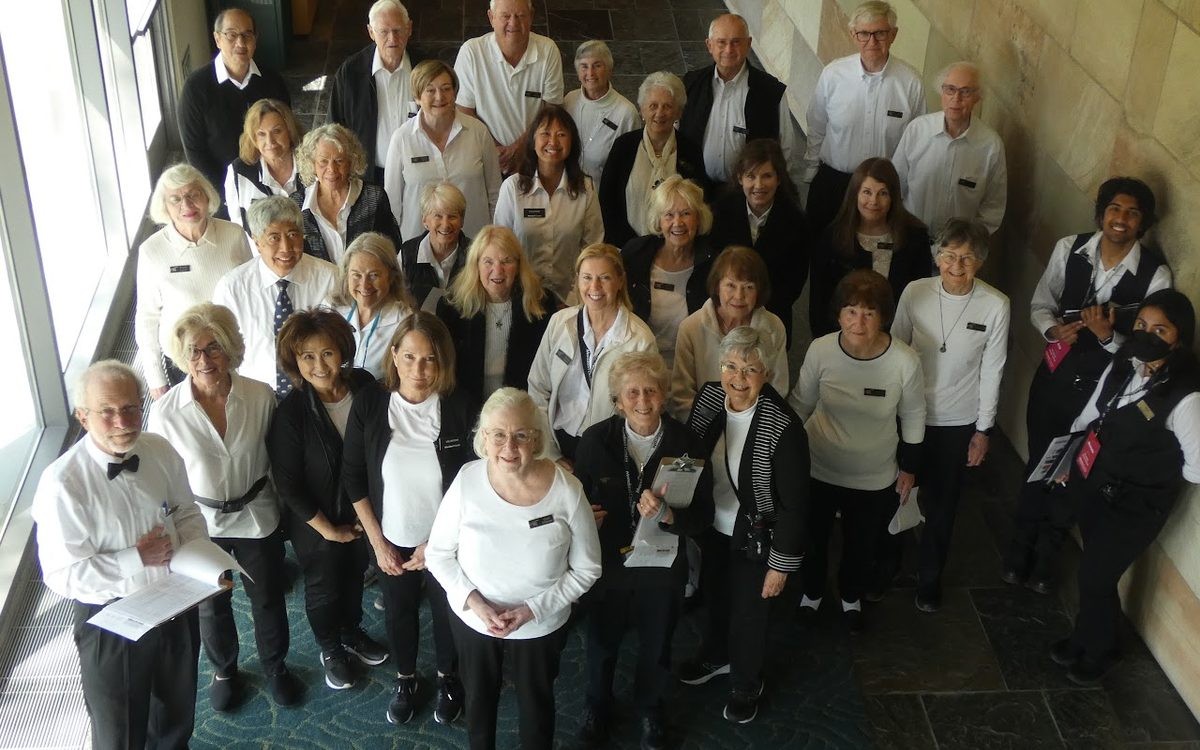 A crowd of people wearing black and white attire, gathered indoors, smiling at the camera.