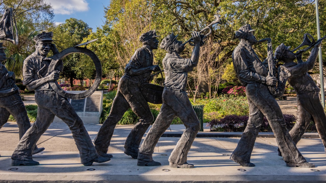 Statues of five marching musicians playing instruments in a sunny park