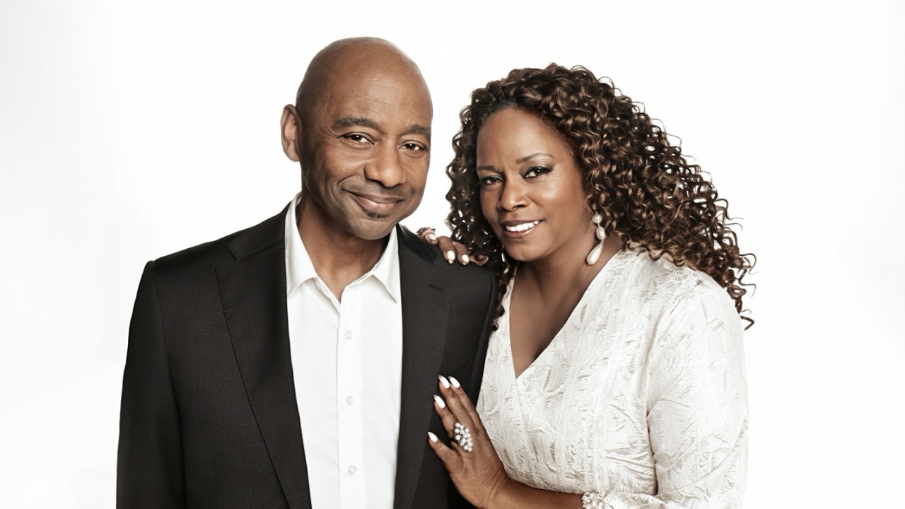 Branford Marsalis in black suit, Dianne Reeves in a white blouse, hand on his chest