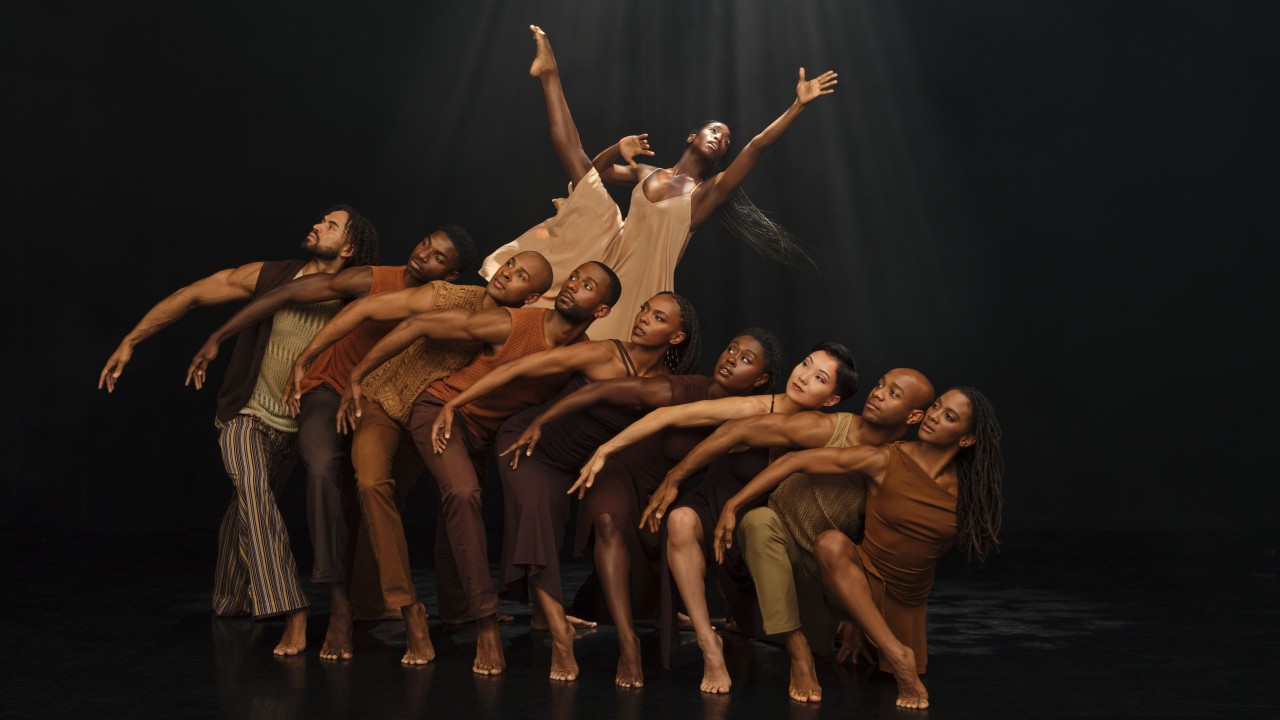 A dynamic group of dancers posed dramatically against a dark background.