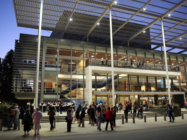 Crowd of people gathering outside a modern building at twilight.