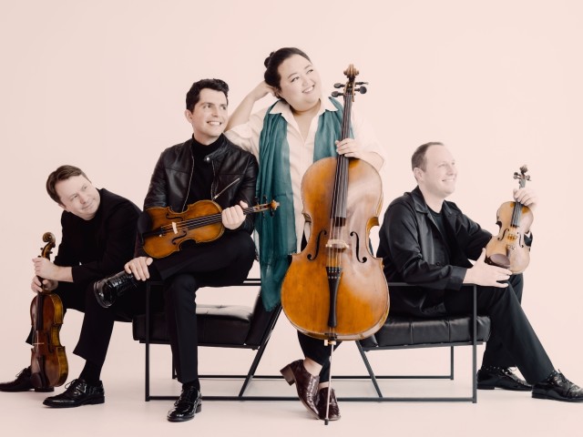 Calidore String Quartet seated with violins and a cello against a pale pink background