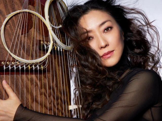 Yumi Kurosawa poses next to a large instrument with circular elements.
