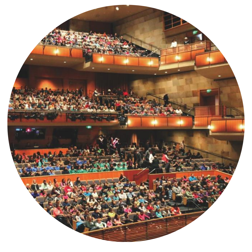 A crowded auditorium filled with an audience seated on multiple levels.