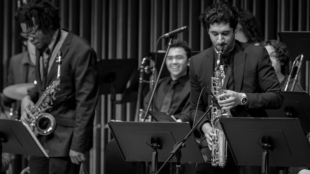 Black-and-white photo of three jazz musicians: two saxophonists and a smiling drummer