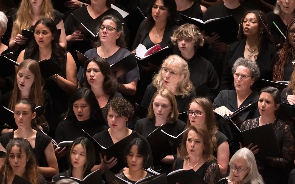 Women's choir in black attire singing from sheet music