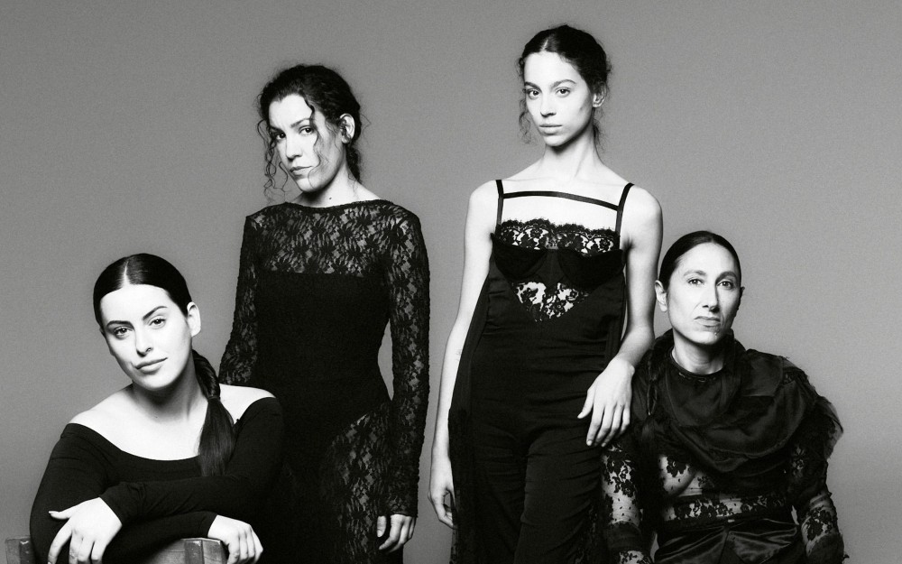 Black-and-white photo of Las Migas in elegant black dresses.