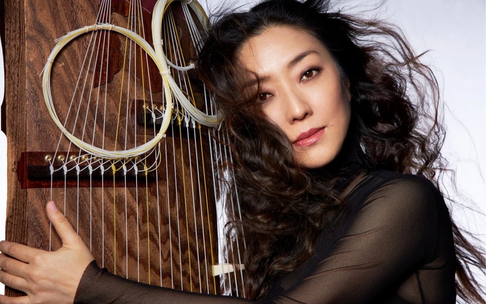 Yumi Kurosawa poses next to a large instrument with circular elements.