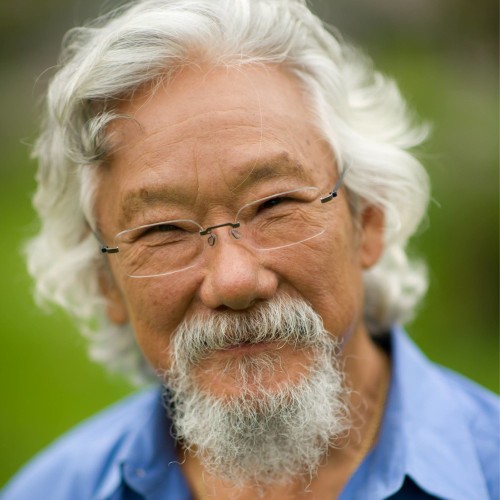David Suzuki with white hair and a beard, wearing glasses and a blue shirt.