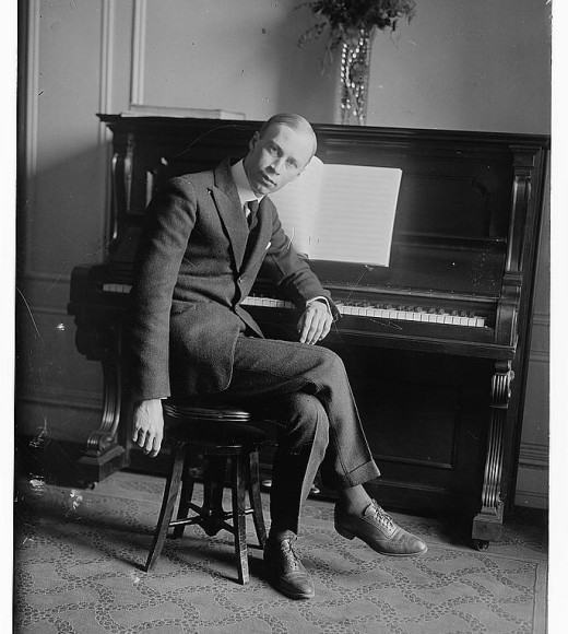 Prokofiev in suit seated at upright piano, black-and-white photograph