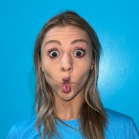 Woman making a fish-face, wide-eyed, in a photograph with bright blue background