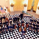 DHS Baroque Ensemble in a grand hall with checkered floor and elegant decor.