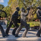 Statues of five marching musicians playing instruments in a sunny park