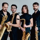 Arcis musicians holding their instruments, dressed in black against a light background.