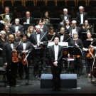 Auburn symphony orchestra on stage, with musicians in formal attire the conductor in front.