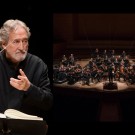 Jordi Saval conductor beside full orchestra on concert stage