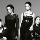 Black-and-white photo of Las Migas in elegant black dresses.