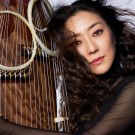 Yumi Kurosawa poses next to a large instrument with circular elements.
