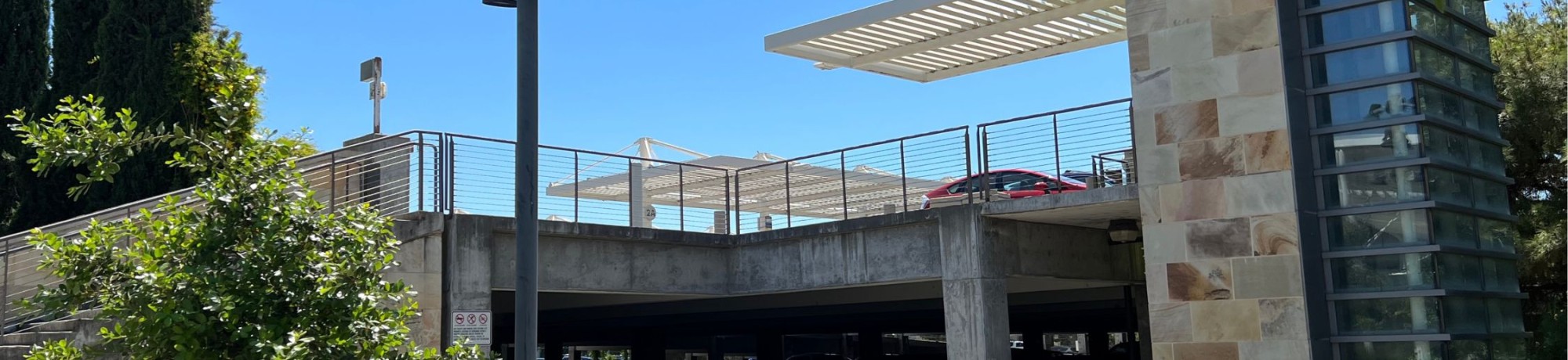 Parking structure with modern design and greenery under clear blue sky.