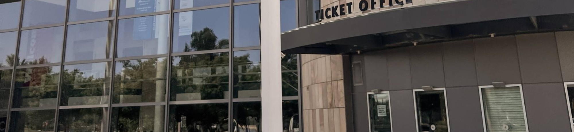 Mondavi Center ticket office with a stone facade and large glass windows in a landscaped area.